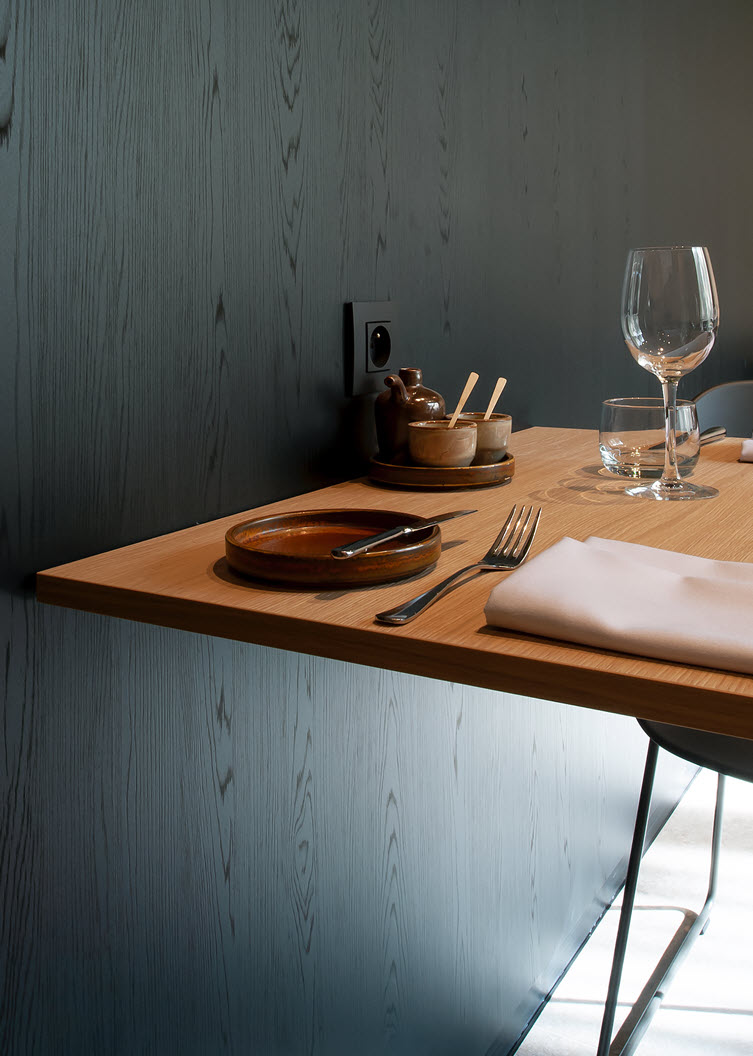 Table with the natural wood colour of Master Oak in contrast to the black Clicwall wall